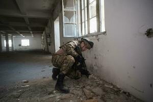 soldier in action near window changing magazine and take cover photo