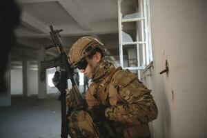 soldier in action near window changing magazine and take cover photo