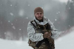 Winter war in the Arctic mountains. Operation in cold conditions.Soldier in winter camouflaged uniform in Modern warfare army on a snow day on forest battlefield with a rifle. Selective focus photo