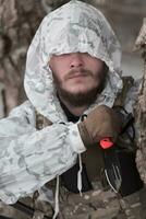 Winter war in the Arctic mountains. Operation in cold conditions.Soldier in winter camouflaged uniform in Modern warfare army on a snow day on forest battlefield with a rifle. Selective focus photo