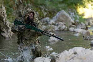 un militar hombre o airsoft jugador en un camuflaje traje furtivo el río y objetivos desde un francotirador rifle a el lado o a objetivo. foto