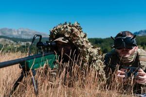 Sniper soldier assisted by an assistant to observe the area to be targeted with modern warfare tactical virtual reality goggles aerial drone military technology. photo