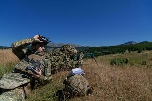 francotirador soldado asistido por un asistente a observar el zona a ser dirigido con moderno guerra táctico virtual realidad gafas de protección aéreo zumbido militar tecnología. foto