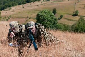 Sniper soldier assisted by an assistant to observe the area to be targeted with modern warfare tactical virtual reality goggles aerial drone military technology. photo