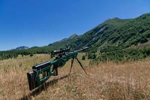 un verde militar francotirador rifle con un alcance para largo distancia táctico moderno guerra en amarillo césped azul cielo foto