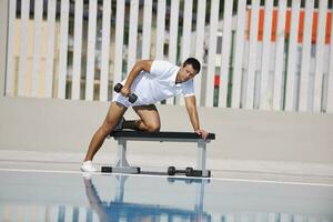 joven hombre ejercicio a junto a la piscina foto