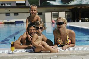 familia joven feliz divertirse en la piscina foto