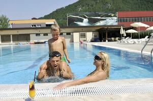 familia joven feliz divertirse en la piscina foto