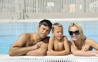 familia joven feliz divertirse en la piscina foto