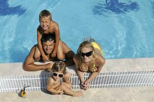 familia joven feliz divertirse en la piscina foto