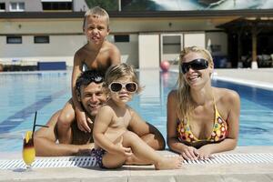 familia joven feliz divertirse en la piscina foto