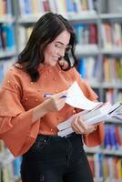 the student uses a notebook and a school library photo