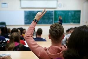 The student raises his hands asking a question in class in college photo