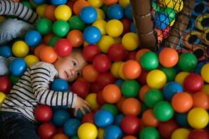 chico teniendo divertido en cientos de vistoso el plastico pelotas foto