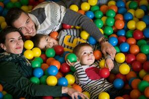 padres jóvenes con hijos en una sala de juegos para niños foto