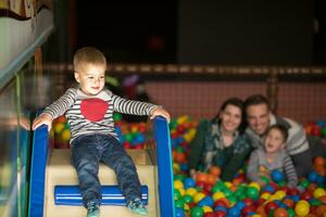 padres jóvenes con hijos en una sala de juegos para niños foto