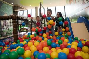 madre joven con sus hijos en una sala de juegos para niños foto