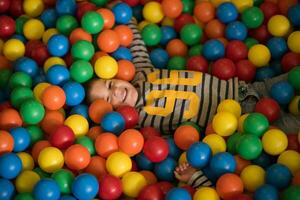 chico teniendo divertido en cientos de vistoso el plastico pelotas foto