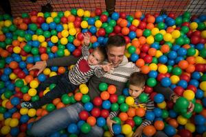 Young dad with kids in a children's playroom photo