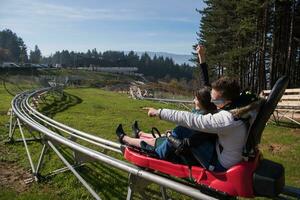 pareja disfruta conduciendo en una montaña rusa alpina foto