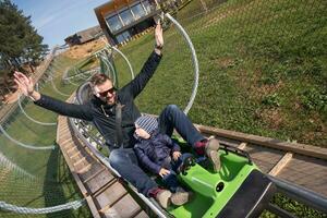 father and son enjoys driving on alpine coaster photo