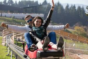 pareja disfruta conduciendo en una montaña rusa alpina foto