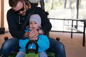 padre e hijo disfrutan conduciendo en montaña rusa alpina foto