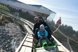 padre e hijo disfrutan conduciendo en montaña rusa alpina foto