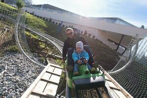 padre e hijo disfrutan conduciendo en montaña rusa alpina foto