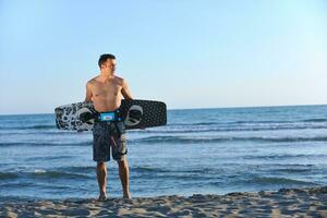 Portrait of a young  kitsurf  man at beach on sunset photo