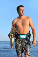 Portrait of a young  kitsurf  man at beach on sunset photo