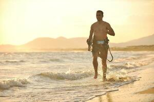 Portrait of a young  kitsurf  man at beach on sunset photo