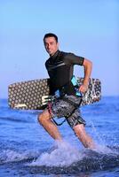 Portrait of a young  kitsurf  man at beach on sunset photo