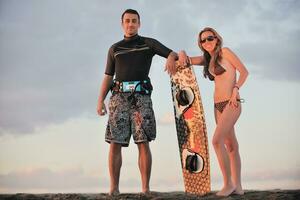 surf couple posing at beach on sunset photo