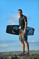 Portrait of a young  kitsurf  man at beach on sunset photo