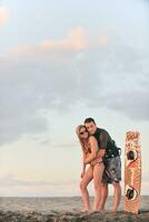 pareja de surf posando en la playa al atardecer foto