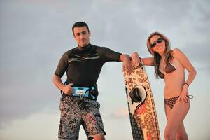 surf couple posing at beach on sunset photo