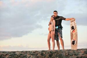 surf couple posing at beach on sunset photo