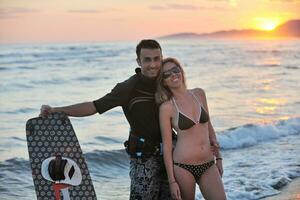 pareja de surf posando en la playa al atardecer foto