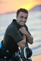 Portrait of a young  kitsurf  man at beach on sunset photo