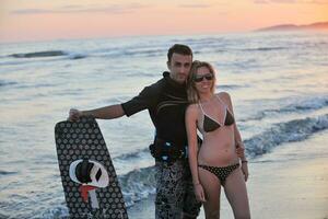 surf couple posing at beach on sunset photo