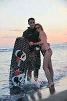 surf couple posing at beach on sunset photo
