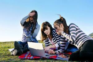 grupo de adolescentes trabajando en una laptop al aire libre foto