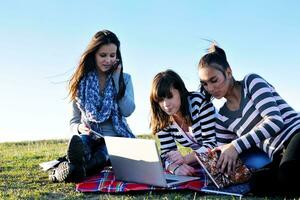 grupo de adolescentes trabajando en una laptop al aire libre foto