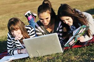 grupo de adolescentes trabajando en una laptop al aire libre foto