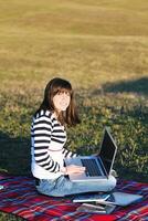 Joven adolescente trabaja en una laptop al aire libre foto