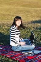 Joven adolescente trabaja en una laptop al aire libre foto