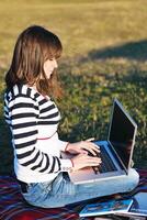 Joven adolescente trabaja en una laptop al aire libre foto