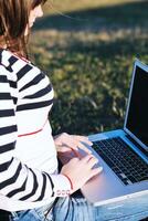 Joven adolescente trabaja en una laptop al aire libre foto