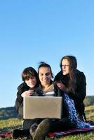 group of teens working on laptop outdoor photo